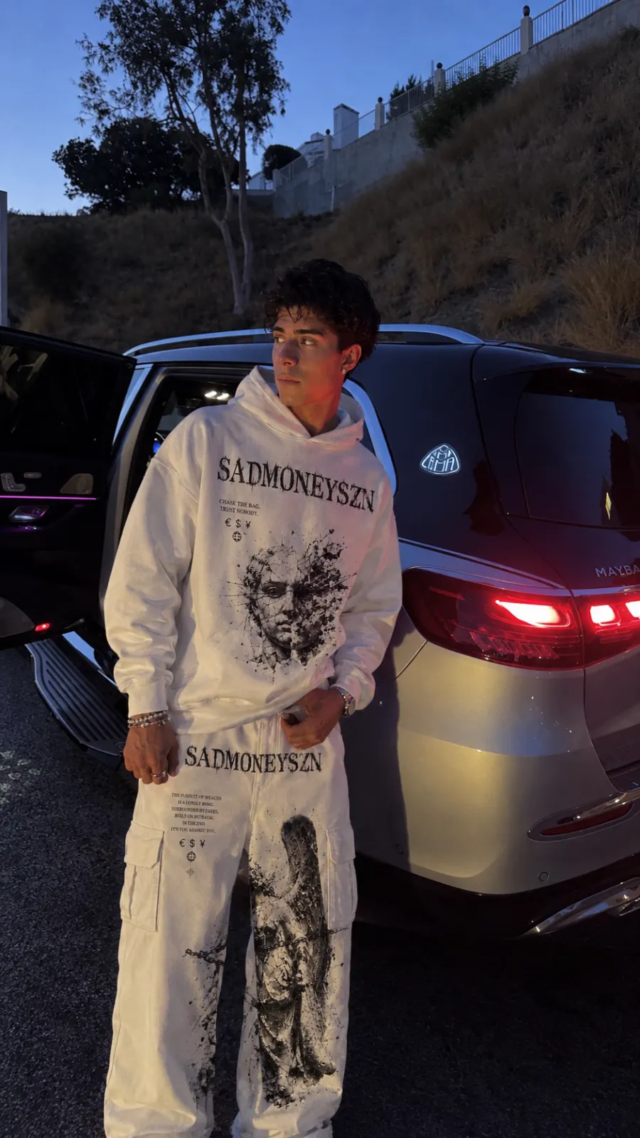 SADMONEYSZN® bone hoodie worn with cargo pants at dusk